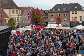 Das Bild zeigt den Marktplatz mit einer Bühne, Ständen und vielen Besucherinnen und Besuchern.