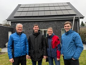 Das Foto zeigt fünf Herren vor einem Haus mit PV_Anlage auf dem Dach.