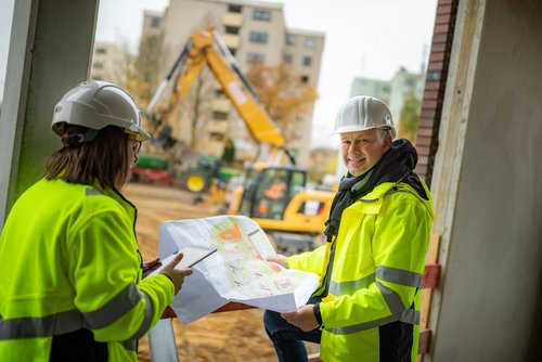 Mitarbeitende besprechen Pläne auf einer Baustelle