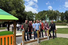 Das Bild zeigt Menschen auf der rollstuhlgerechten Zufahrt zum Sandspielhaus.