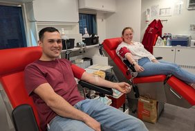 Das Foto zeigt die beiden Personen bei der Blutspende.