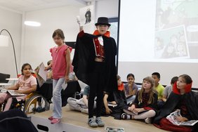 Das Foto zeigt Kinder auf der Bühne. Zum Teil tragen sie Vampir-Umhänge.