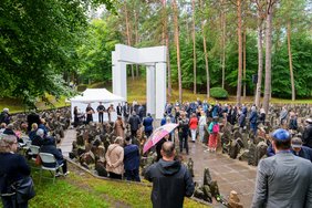 Das Foto zeigt viele Menschen vor der Gedenkstätte im Wald.