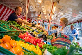 Das Bild zeigt eine Frau beim Einkauf am Marktstand.