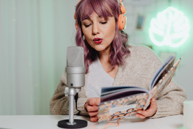 Storytelling in der VHS Dülmen Frau mit rosa Haaren und Buch spricht in ein Mikro