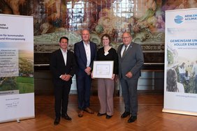 Josef Hovenjürgen, Parlamentarischer Staatssekretär im Ministerium für Heimat, Kommunales, Bau und Digitalisierung des Landes NRW (re.), und Christian Mildenberger, Geschäftsführer von NRW.Energy4Climate (li.), überreichten die Auszeichnung an Dülmens Klimaschutzmanagerin Carolin Dietrich und Reiner Tippkötter vom begleitenden Büro energielenker. Foto: Philip Lehmann, NRW.Energy4Climate