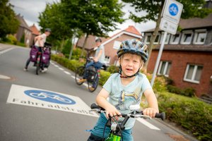 Dieses Foto zeigt ein Kind mit seinem Fahrrad auf einer Fahrradstraße