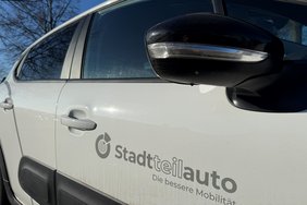 Das Foto zeigt ein weißes Auto mit der Aufschrift "Stadtteilauto".
