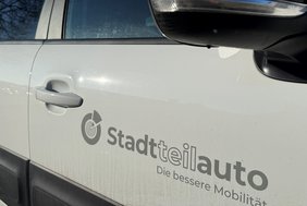 Das Bild zeigt ein weißes Auto mit dem Logo "Stadtteilauto".