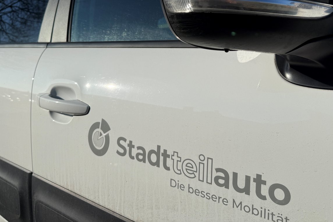 Das Bild zeigt ein weißes Auto mit dem Logo "Stadtteilauto".
