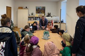 Das Foto zeigt die Kinder mit dem Bürgermeister am Besprechungstisch in seinem Büro.