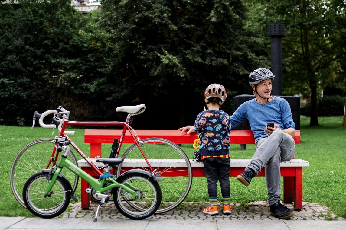 Das Foto zeigt Vater und Sohn auf einer Parkbank, daneben stehen zwei Fahrräder.