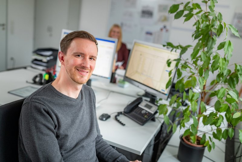 Mitarbeiter sitzt am Schreibtisch vor einem Computer.