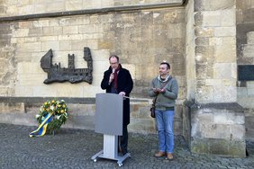 Pfarrdechant Markus Trautmann und der aus Syrien geflüchtete Saad Antoun zeigten mit einem Bombensplitter ein Relikt der damaligen Ereignisse und überreichten es an Bürgermeister Carsten Hövekamp.