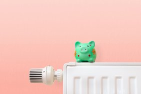 heating costs, green piggy bank on heating radiator Dieses Foto zeigt ein Sparschwein, dass auf einer Heizung steht.