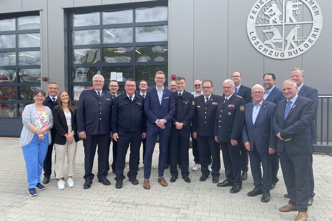 Vertreterinnen und Vertreter von Feuerwehr, Politik und Verwaltung stehen vor dem neuen Feuerwehrgerätehaus in Buldern.