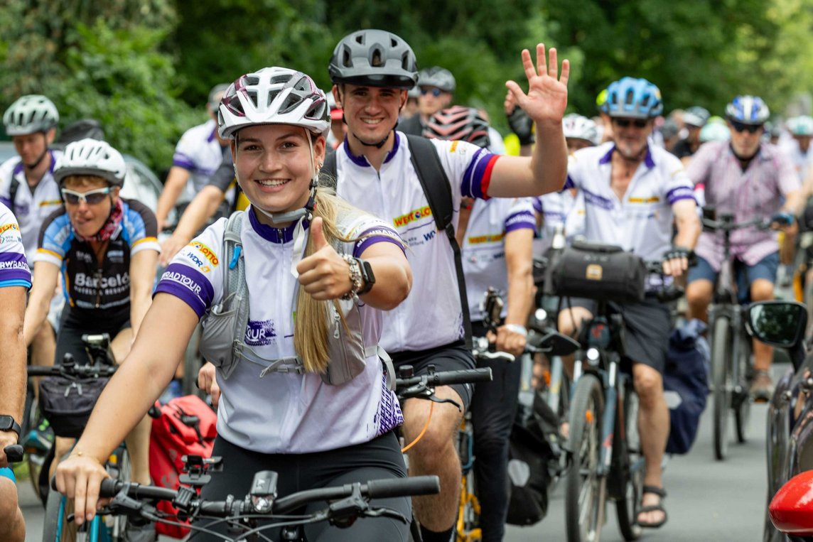 Das Foto zeigt viele gut gelaunte Radfahrerinnen und Radfahrer mit Trikot und Helm.