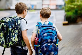 Two little kid boys with backpack or satchel. Schoolkids on the Das Bild zeigt zwei Schulkinder von hinten mit ihrem Tornister.