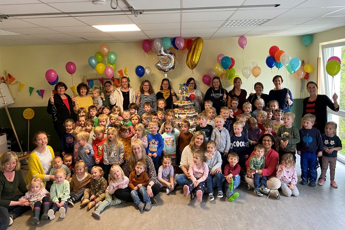 Das Bild zeigt die Kinder und Erzieherinnen des Kindergartens mit der riesigen Torte.