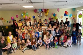Das Bild zeigt die Kinder und Erzieherinnen des Kindergartens mit der riesigen Torte.