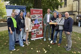 Bürgermeister Carsten Hövekamp (Mitte) übergab einen Präsentkorb an Hilla Berheide vom AKHD (3. v. re.) sowie Leonie und Andreas Steens. Zur Prämierung des bewegenden Fotos, das groß auf dem Banner zu sehen ist, gratulierten die Ehrenamtskoordinatorinnen Verena Rohlmann (2. v. li.) aus Dülmen und Vanessa Kalkhoff (3. v. li.) aus Nottuln sowie Yvonne Steinbuß, hauptamtliche Koordinatorin vom AKHD Südliches Münsterland. Foto: Stadt Dülmen/Kannacher