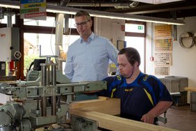 Bürgermeister Carsten Hövekamp (li.) unterstützt Björn Mölder an seinem Arbeitsplatz in der Holzverarbeitung der Werkstätten Karthaus. Foto: Britta Voß