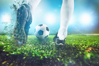 Football scene at night match with close up of a soccer shoe hitting the ball